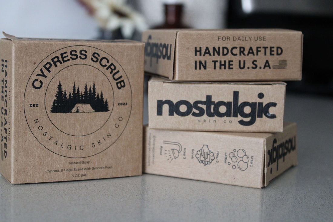 Stacked boxes of Nostalgic Skin Co. handmade bar soaps with eco-friendly packaging, showcasing rustic, natural branding on a clean countertop.”
