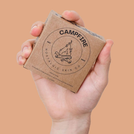 Hand holding Campfire natural soap by Nostalgic Skin Co — a rugged, plant-based soap for men in minimalist kraft packaging.
