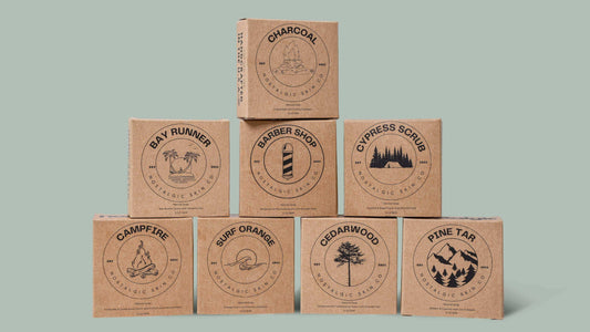 A collection of Nostalgic Skin Co.’s handcrafted natural soap bars for men, featuring various scents and ingredients, displayed on a rustic wooden surface.