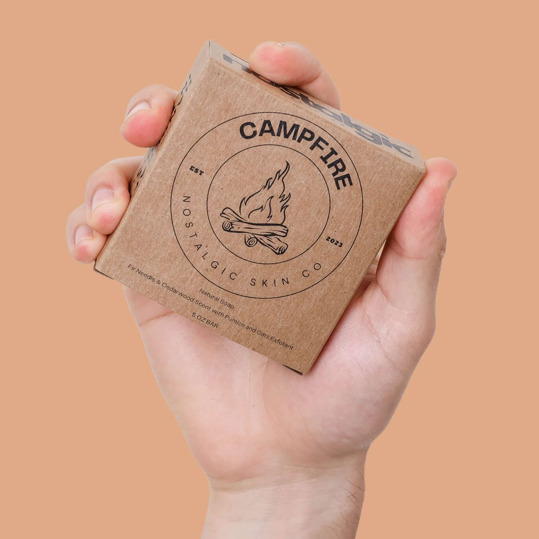 Hand holding Campfire natural soap by Nostalgic Skin Co — a rugged, plant-based soap for men in minimalist kraft packaging.