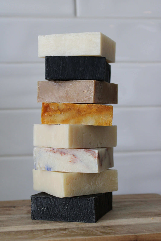 A stack of handcrafted natural soaps neatly arranged on a wooden dish, highlighting their rich texture and eco-friendly ingredients for a refreshing cleanse.