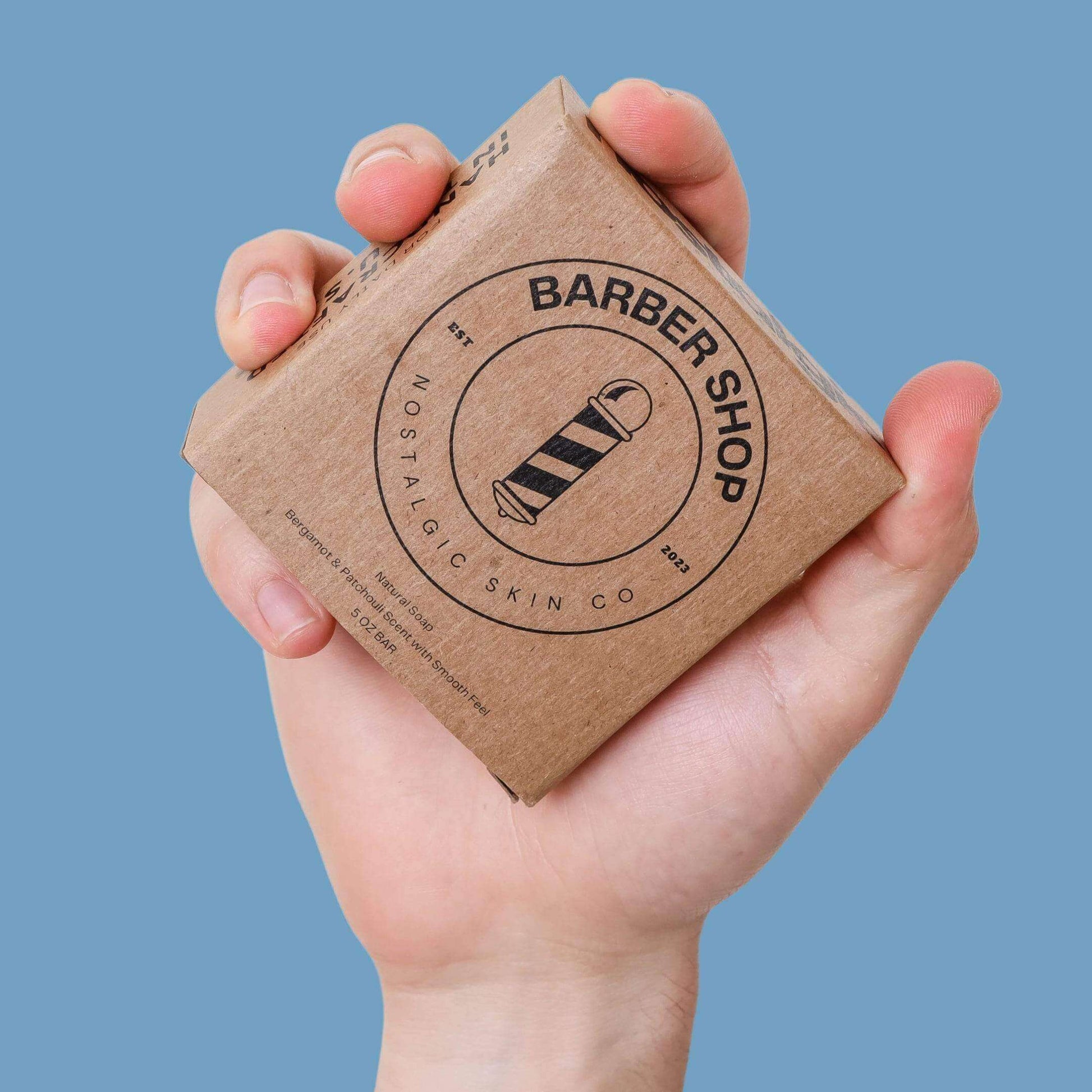 Hand holding Barber Shop bar soap packaging with vintage logo, ideal men's soap for a classic shave experience.