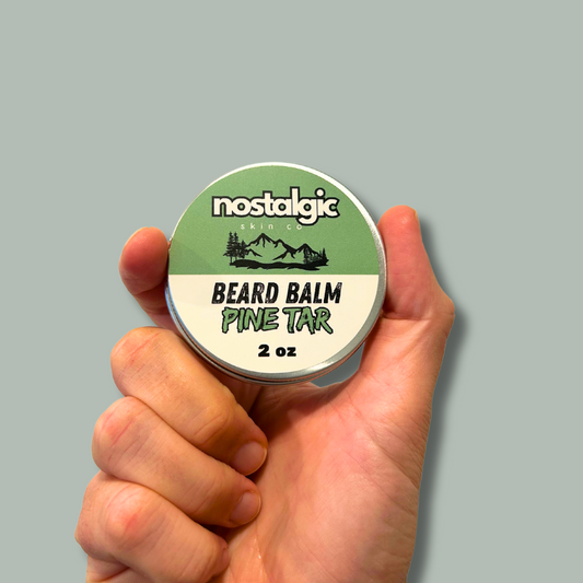 Hand holding Pine Tar Beard Balm tin, perfect for nourishing and taming your beard with natural ingredients.